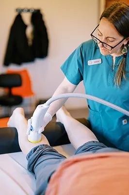 Assistant performing softwave on patients knee.