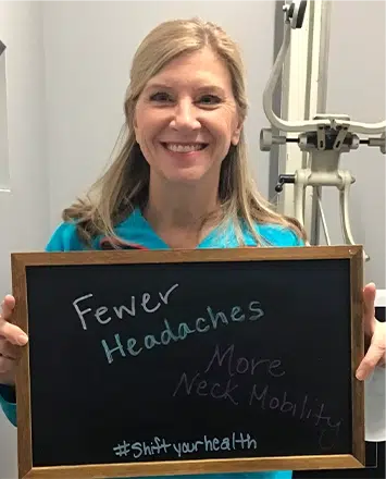 Patient testimonial photo holding a sign highlighting fewer headaches and improved neck mobility.